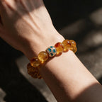 Amber Glow natural citrine bracelet worn on a woman’s wrist, showing its warm golden color and green centerpiece.