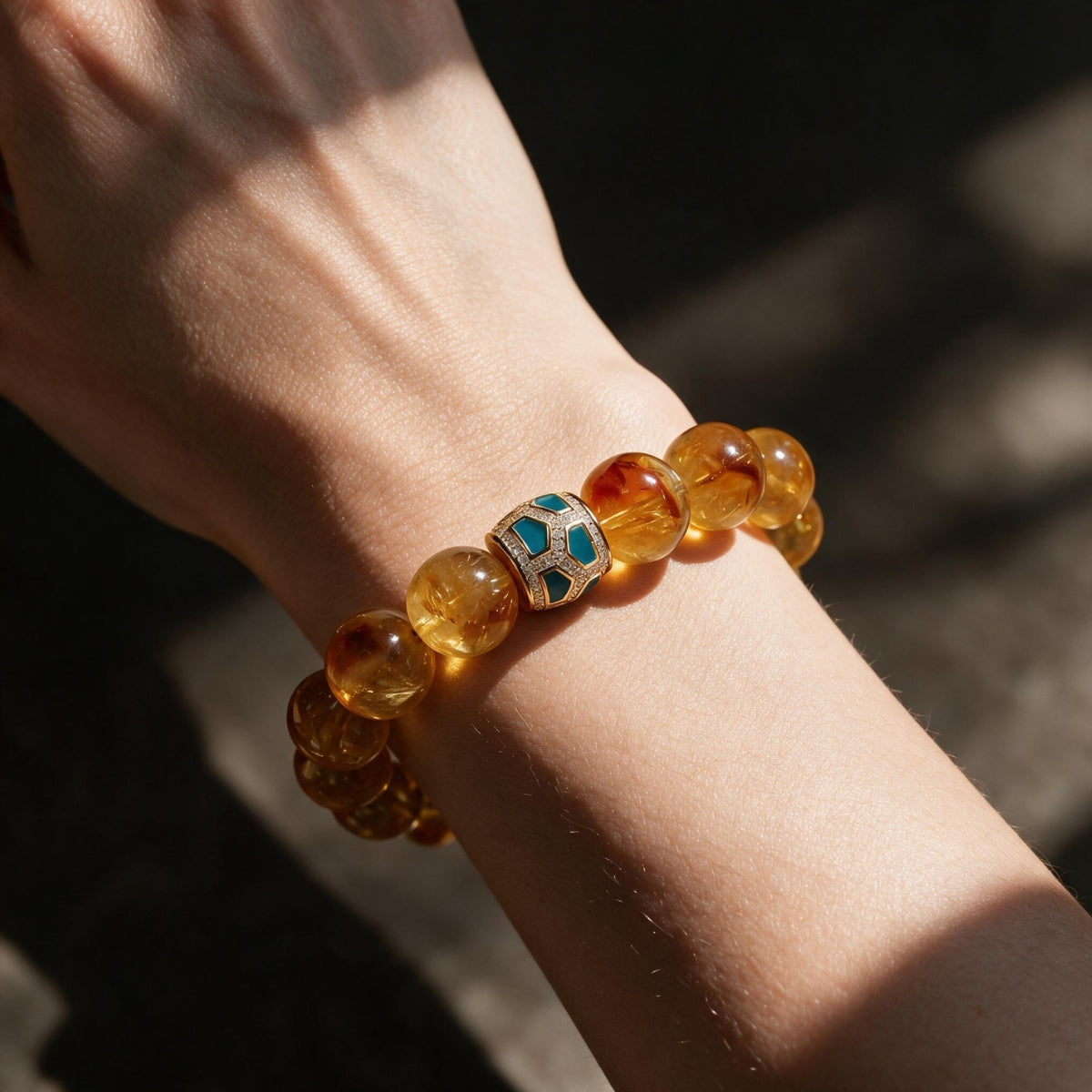 Amber Glow natural citrine bracelet worn on a woman’s wrist, showing its warm golden color and green centerpiece.