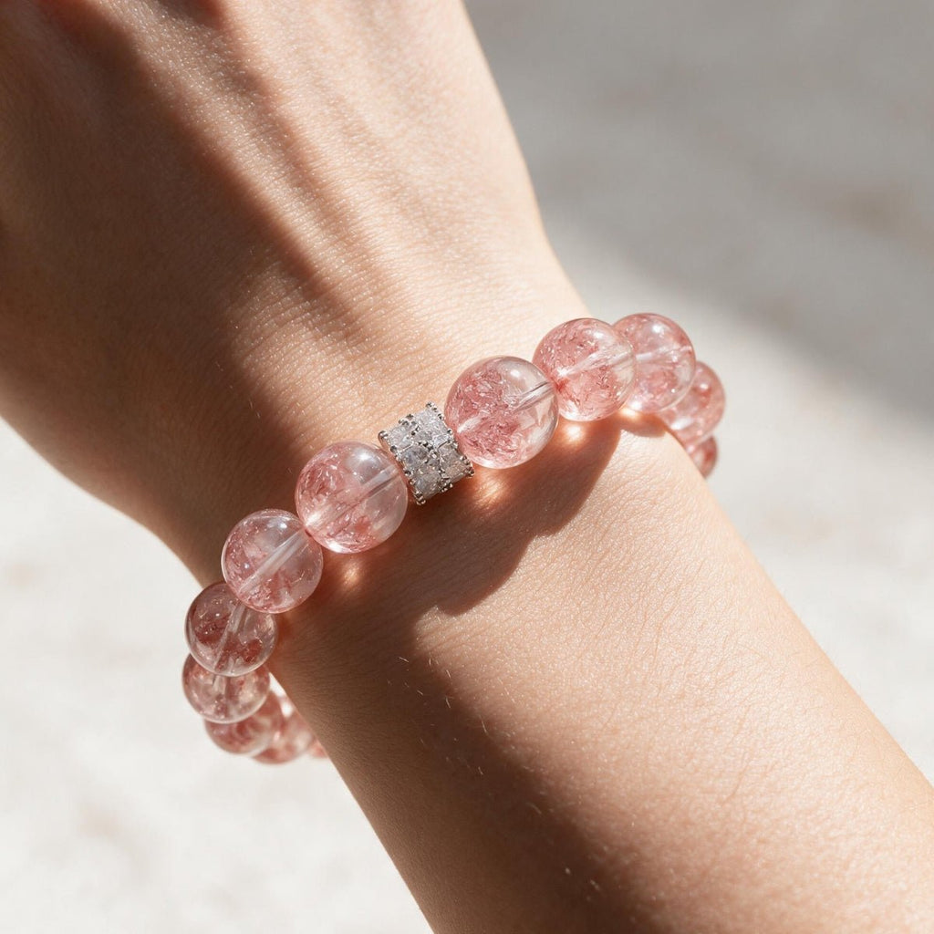 Sunlit wrist wearing the Aurora Bloom Strawberry Quartz bracelet with luminous rosy-pink beads.