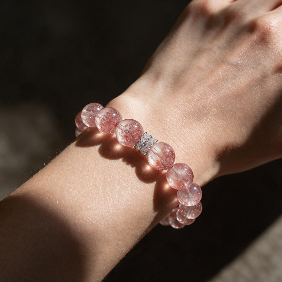 Aurora Bloom Strawberry Quartz bracelet worn on the wrist in warm natural light.