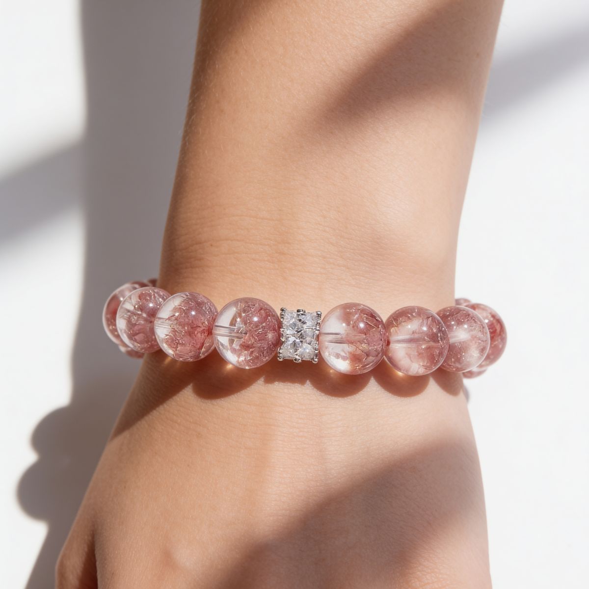 Woman wearing Aurora Bloom Strawberry Quartz Bracelet with 12mm rosy-pink beads and crystal-accent centerpiece