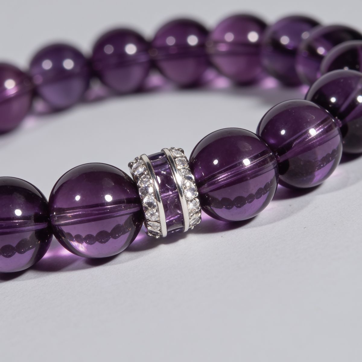 Angled close-up of deep purple Amethyst beads and the sterling silver centerpiece on the Eternal Elegance bracelet.