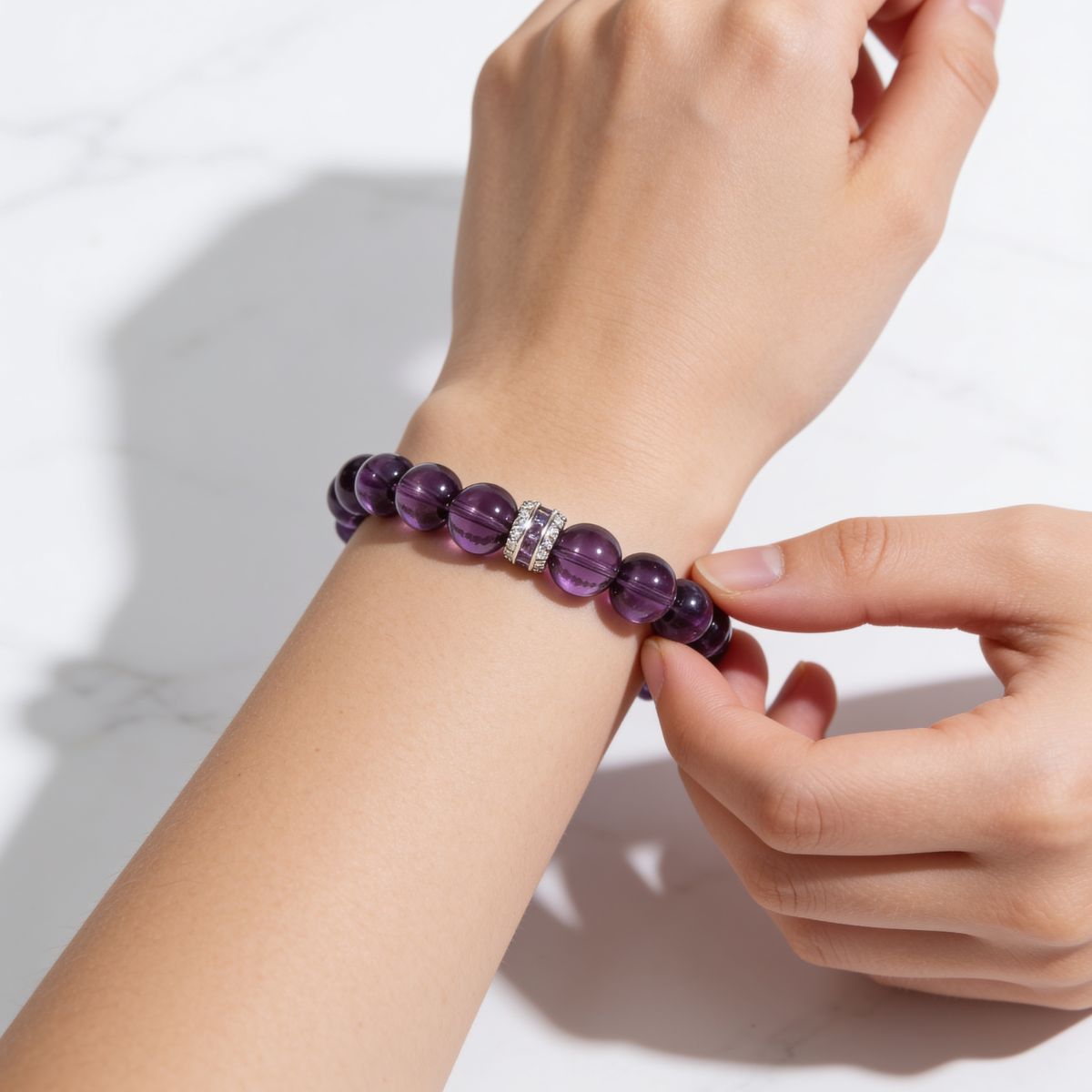 Woman adjusting the Eternal Elegance natural Amethyst stretch bracelet on her wrist.