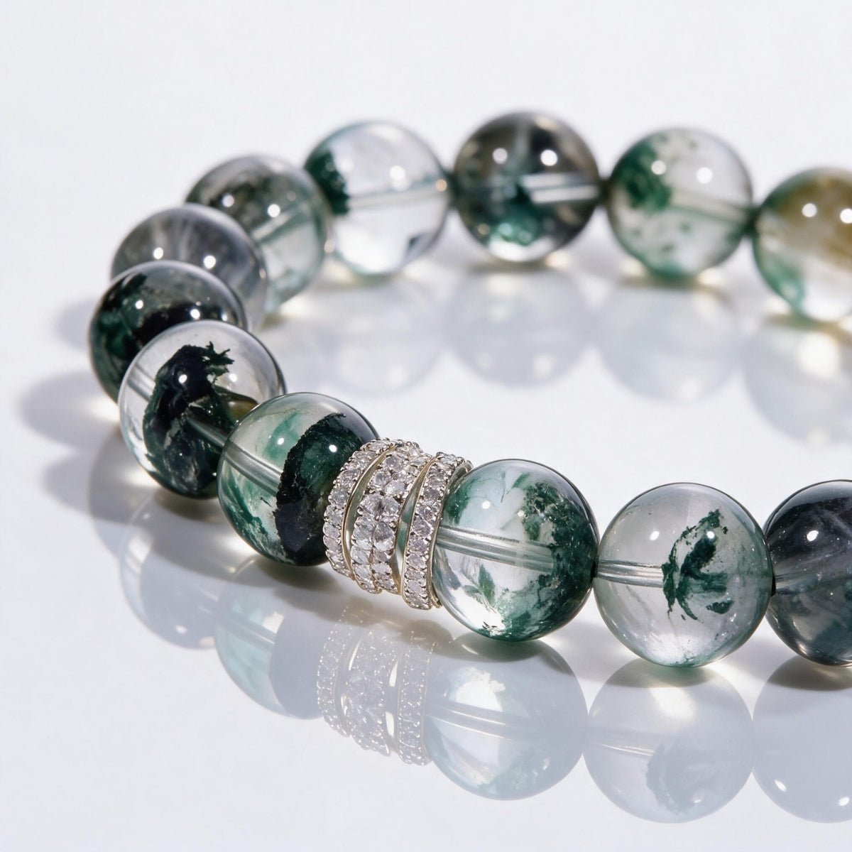 Detailed view of clear quartz beads with layered forest-green phantom inclusions and pavé accents