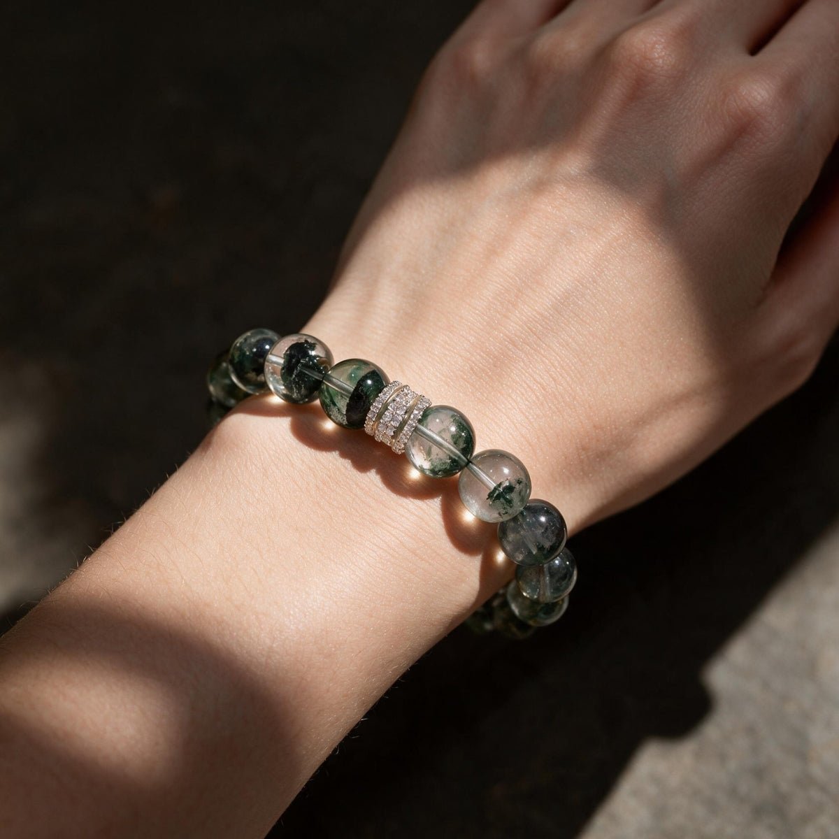 Angled wrist view of the Forest Veil bracelet highlighting its natural green inclusions in sunlight