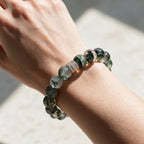 Wrist view of 12mm Green Phantom Quartz beads and the gold-tone centerpiece in soft daylight