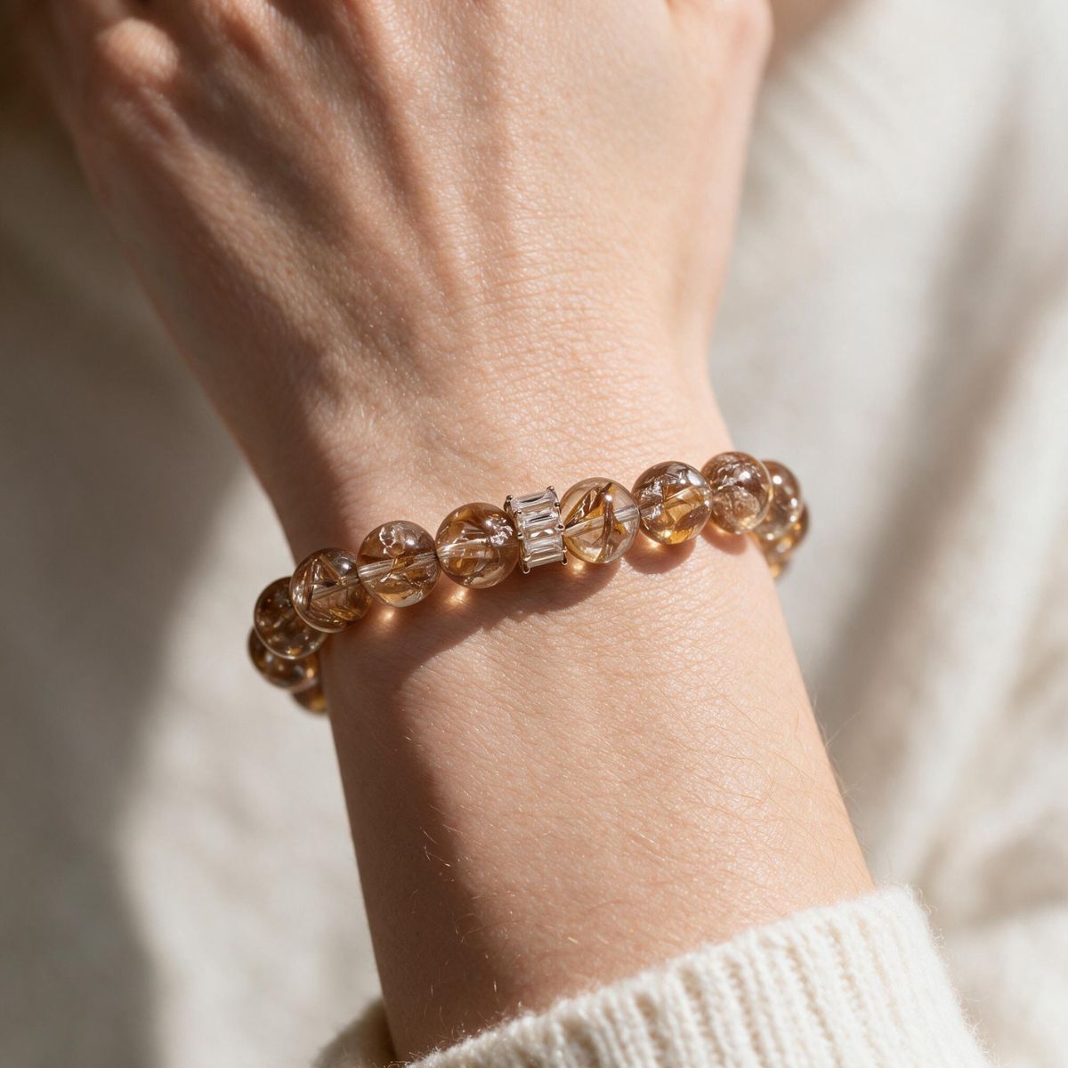 Fortune Koi Hematoid Quartz bracelet styled on the wrist with a soft neutral knit