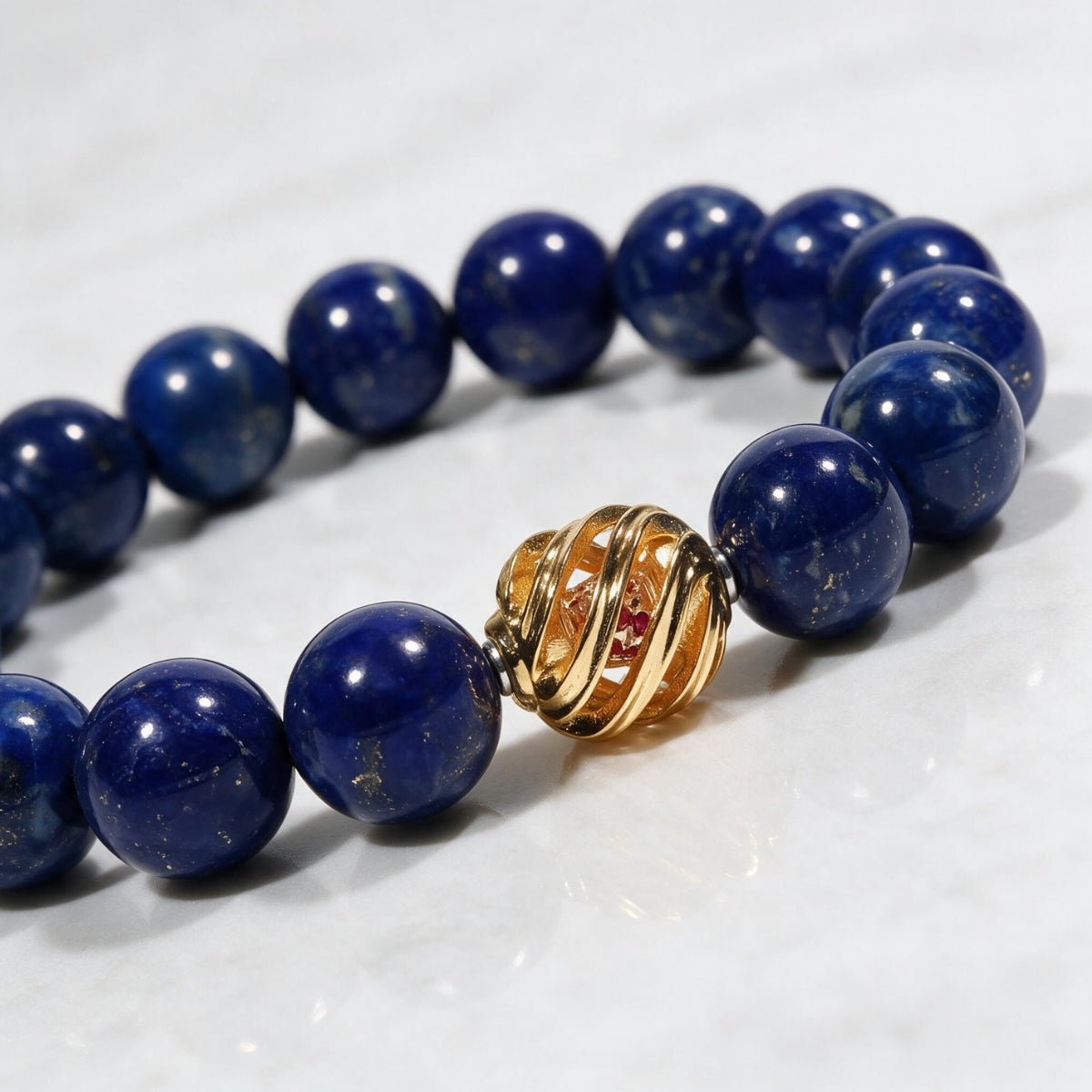 Close-up of polished blue lapis lazuli beads and the symbolic 14K gold-plated centerpiece.