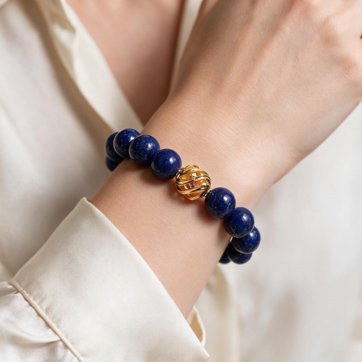 Royal-blue lapis lazuli bracelet with a gold-plated centerpiece styled with a polished white outfit.