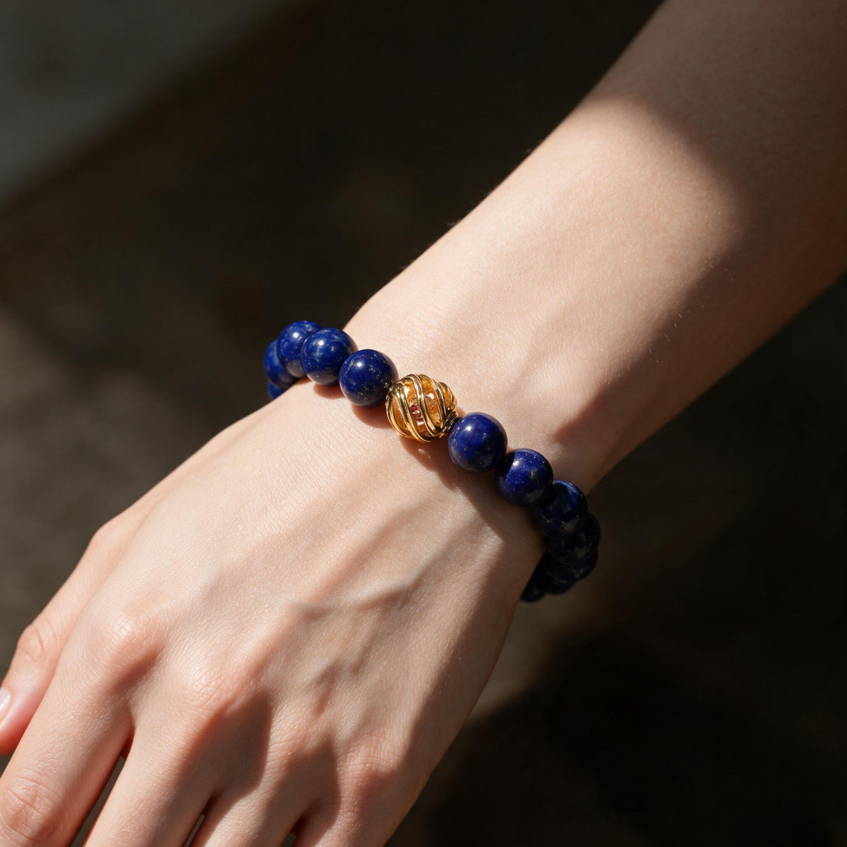 Golden Lucky Lapis Bracelet worn on the wrist in warm light, showing its rich blue and gold contrast.
