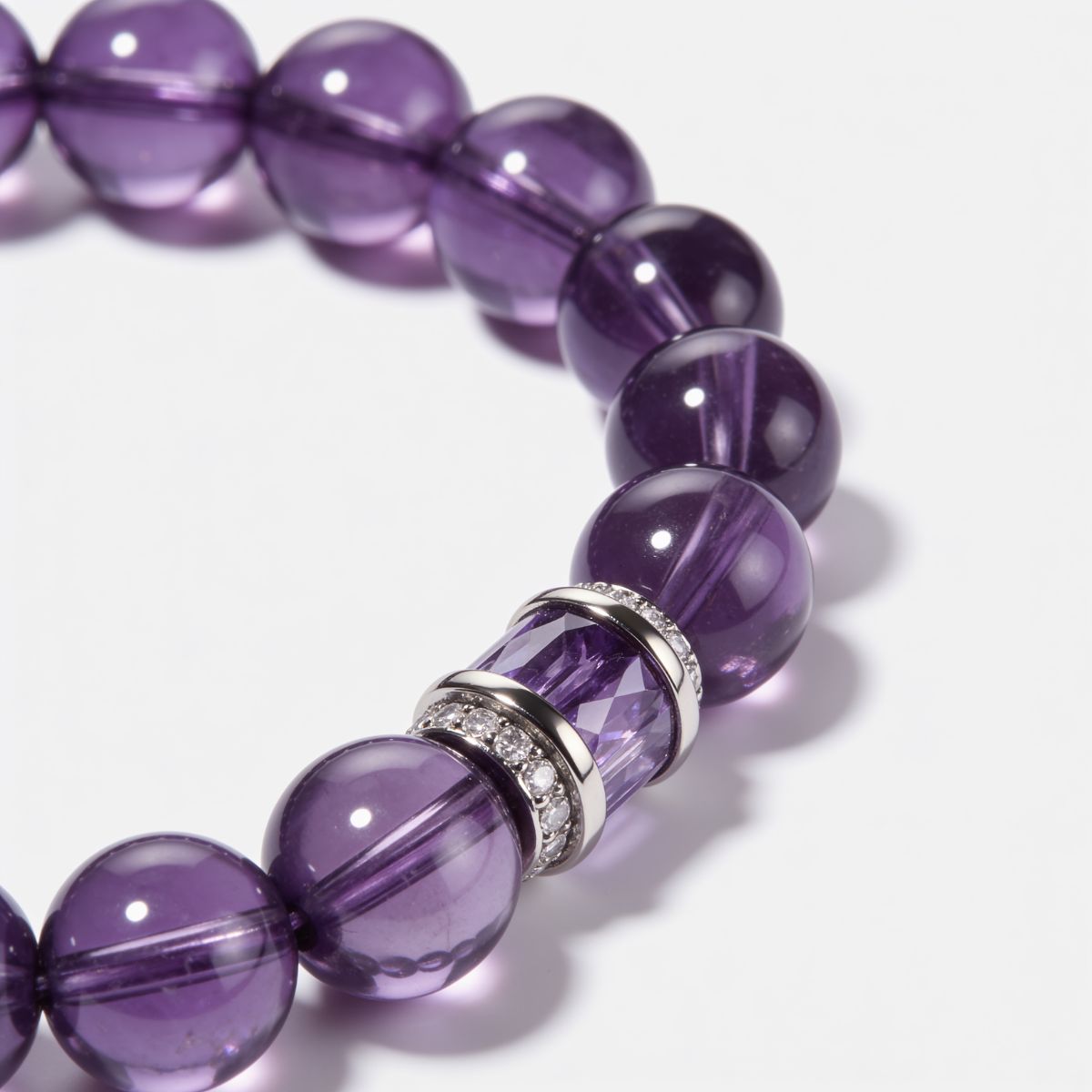 Detailed view of natural Sri Lankan amethyst beads with rich violet tones, polished finish, and sterling silver amethyst inlay centerpiece