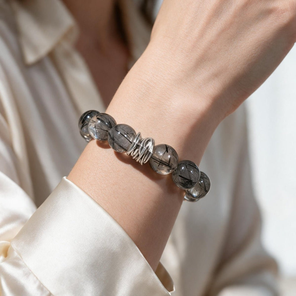 Guardian Black Rutilated Quartz Bracelet styled on a woman's wrist with a polished white sleeve