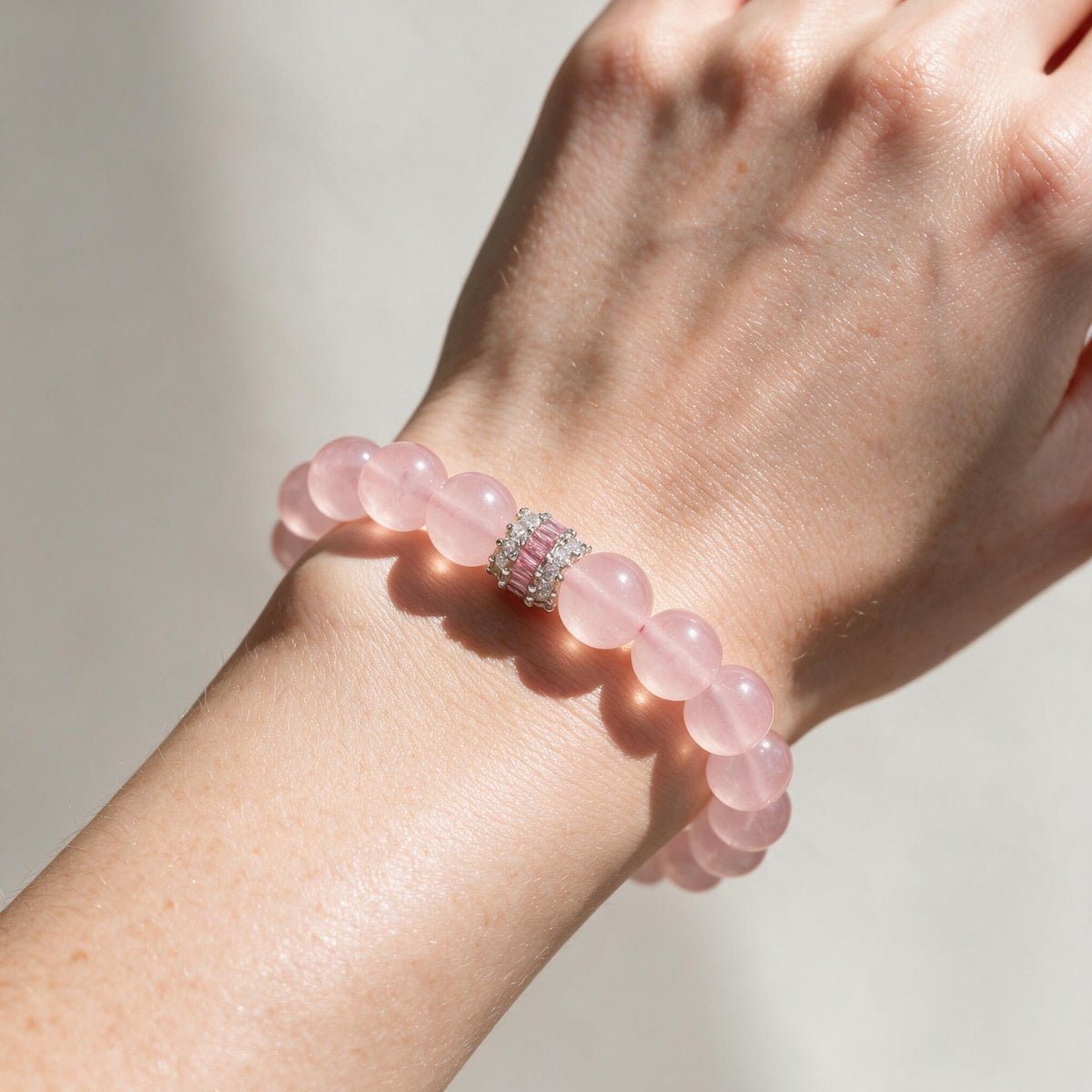 Close wrist view of the 10mm Madagascar Rose Quartz beaded bracelet in natural light