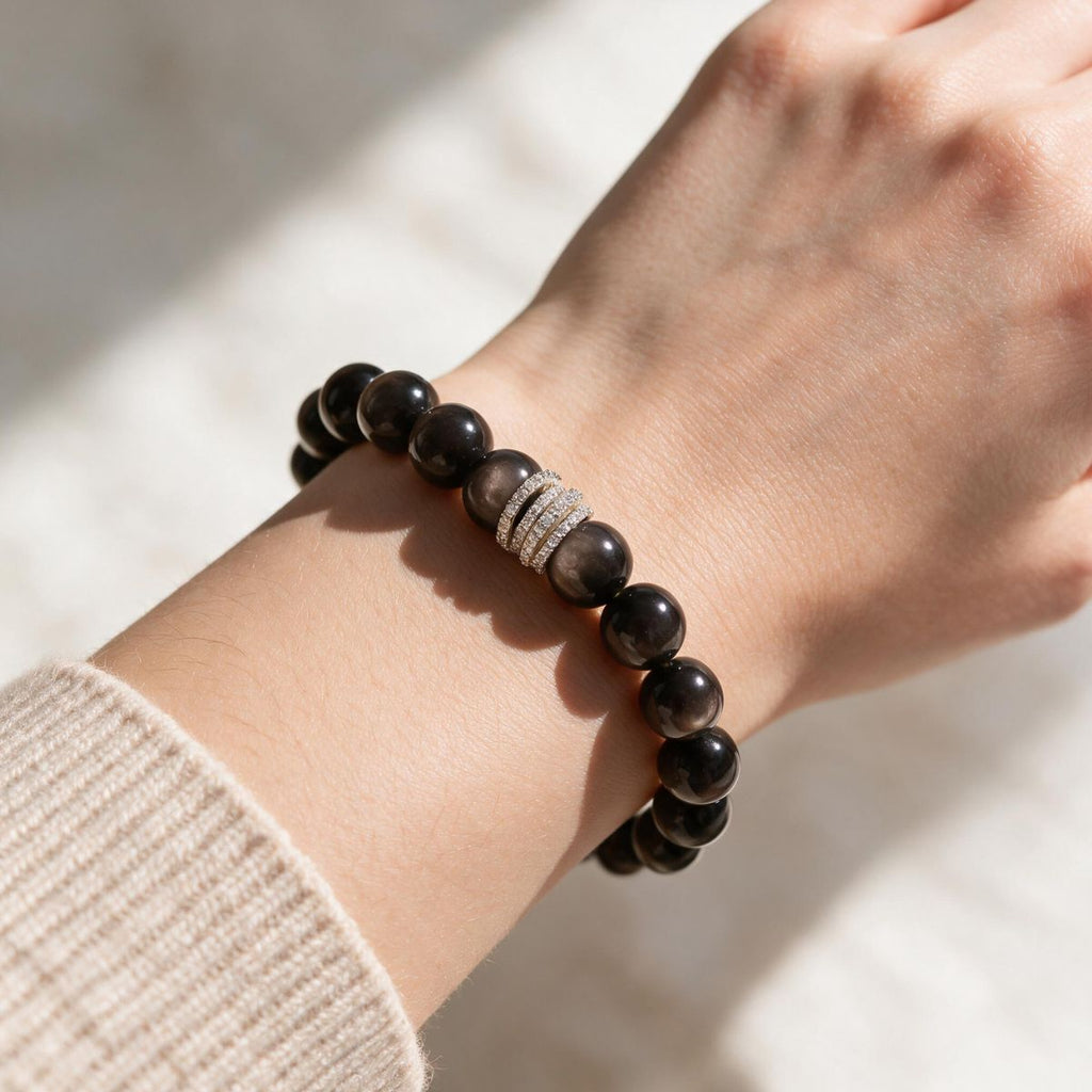 Silver Sheen Obsidian bracelet styled on a woman’s wrist with a neutral knit sleeve.