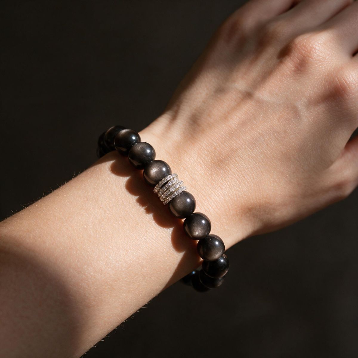 Midnight Shield Silver Sheen Obsidian bracelet worn on a woman’s wrist in soft directional light.