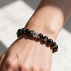 Midnight Shield Silver Sheen Obsidian bracelet worn on a woman’s wrist in natural sunlight.