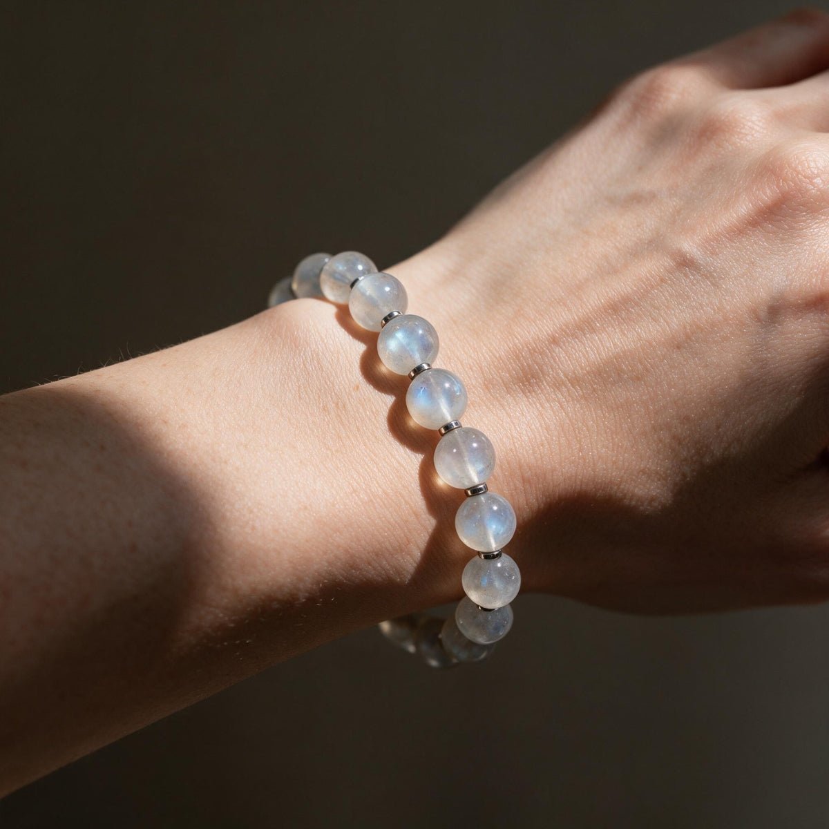 Mystic Moonstone Bracelet worn on a woman’s wrist in sunlight, showing its delicate 8mm profile