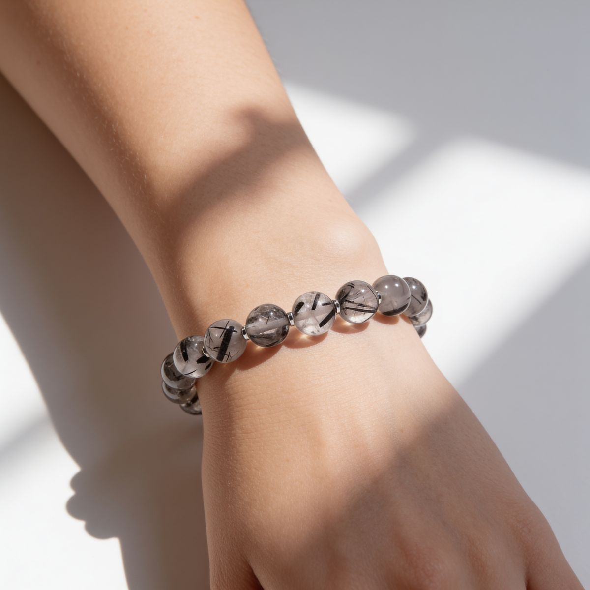 Natural Black Rutilated Quartz bracelet on the wrist with glossy smoky beads and unique black rutile needle patterns.