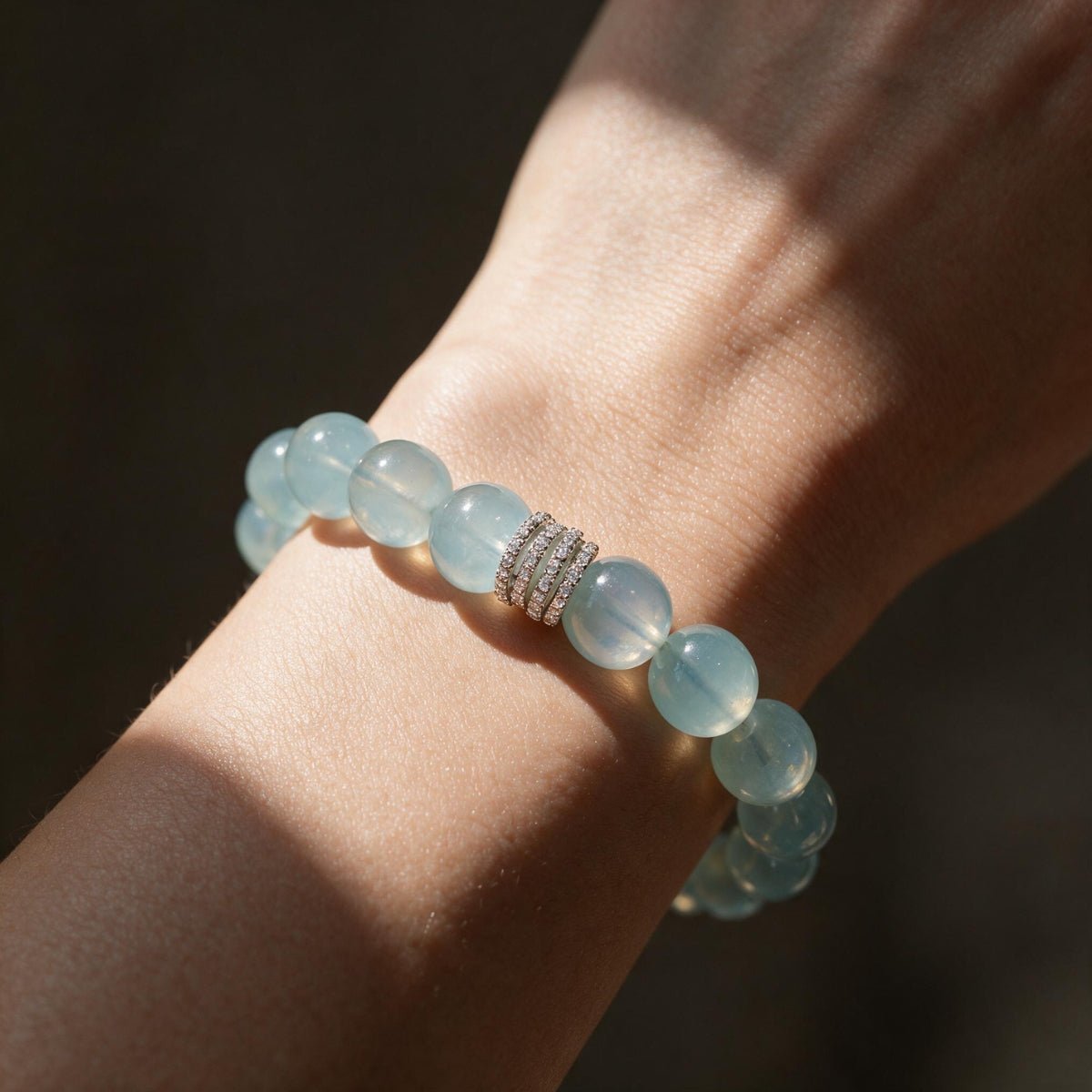 Woman wearing the Ocean Calm 12mm aquamarine bracelet in warm natural sunlight