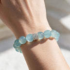 Ocean Calm natural Brazilian aquamarine bracelet with 12mm ocean-blue beads and a silver-tone centerpiece worn on a woman’s wrist.
