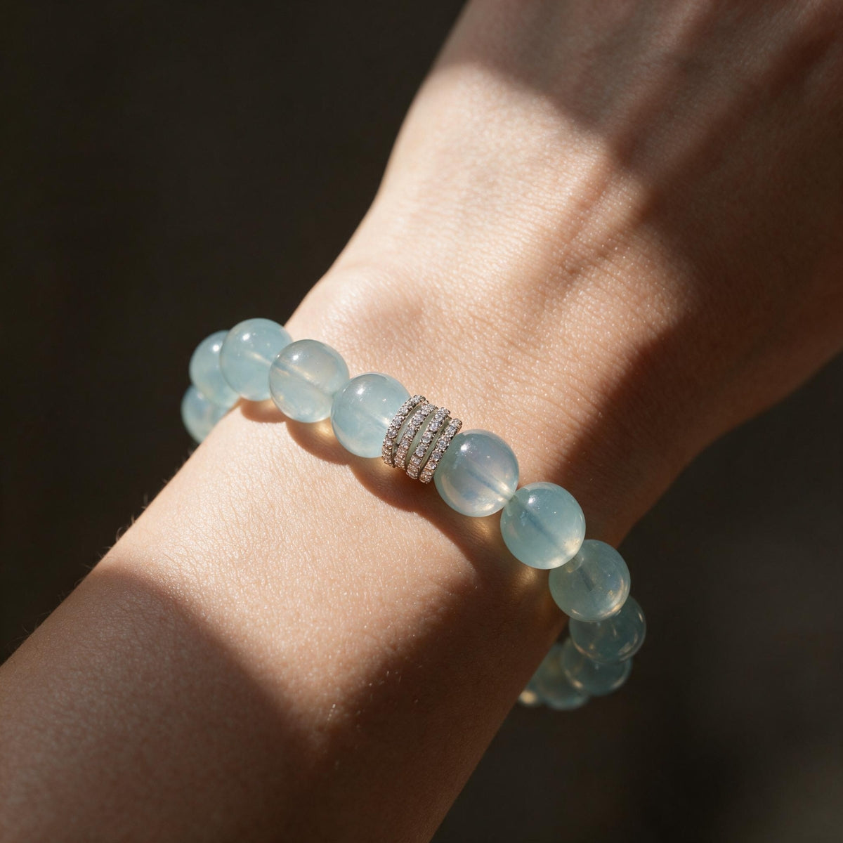 Woman wearing the Ocean Calm 12mm aquamarine bracelet in warm natural sunlight