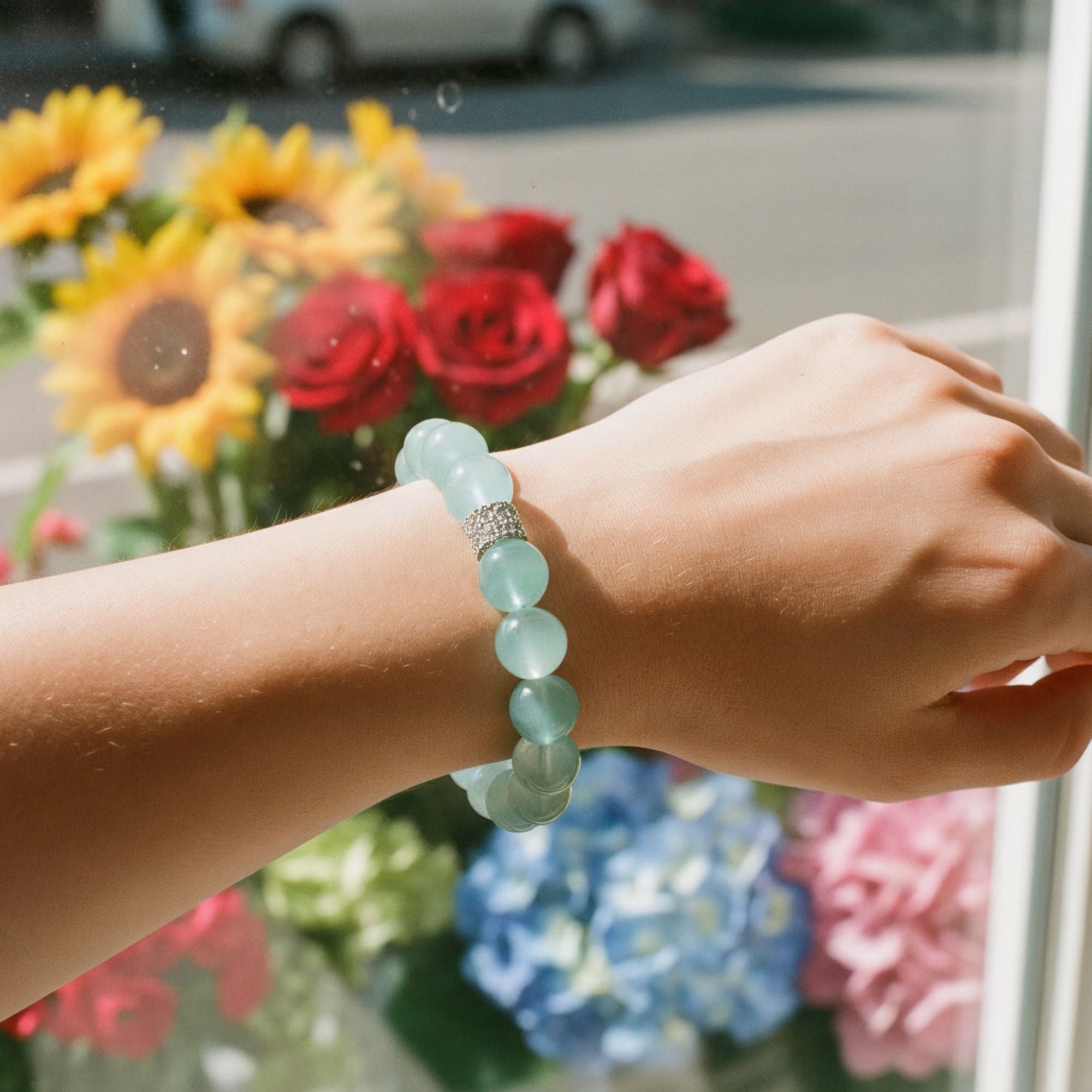 Aquamarine beaded bracelet worn on wrist with colorful flowers in the background
