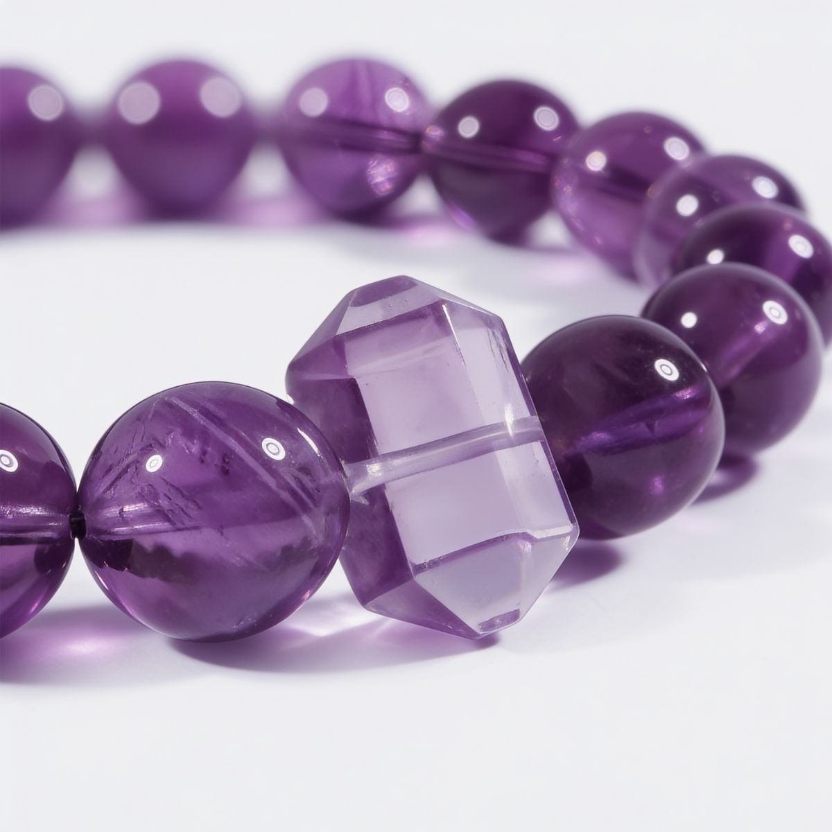 Close-up of natural Sri Lankan amethyst beads showing rich violet tones, soft translucency, and polished amethyst pillar centerpiece