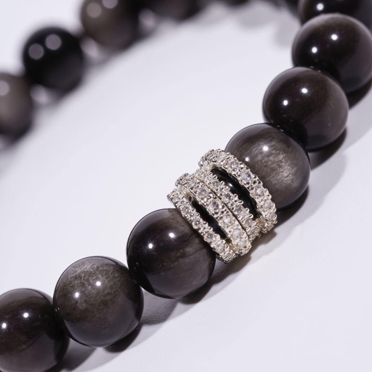 Close-up of Silver Sheen Obsidian beaded bracelet with reflective black beads and sparkling pavé ring centerpiece