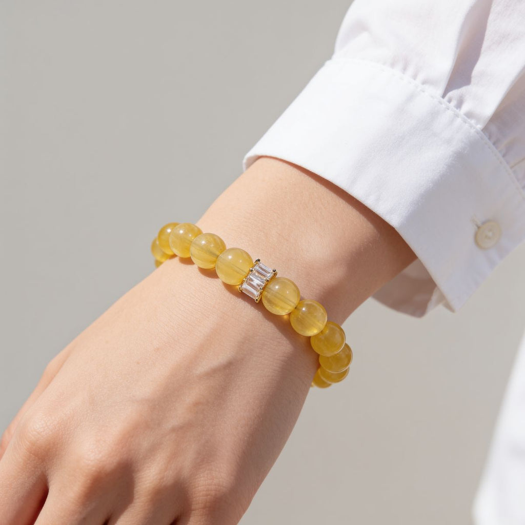 Yellow Fluorite beaded bracelet styled on the wrist with a white shirt and gold-tone centerpiece